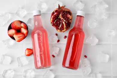 Tasty kombucha in glass bottles, fresh fruits and ice on white tiled table, flat lay