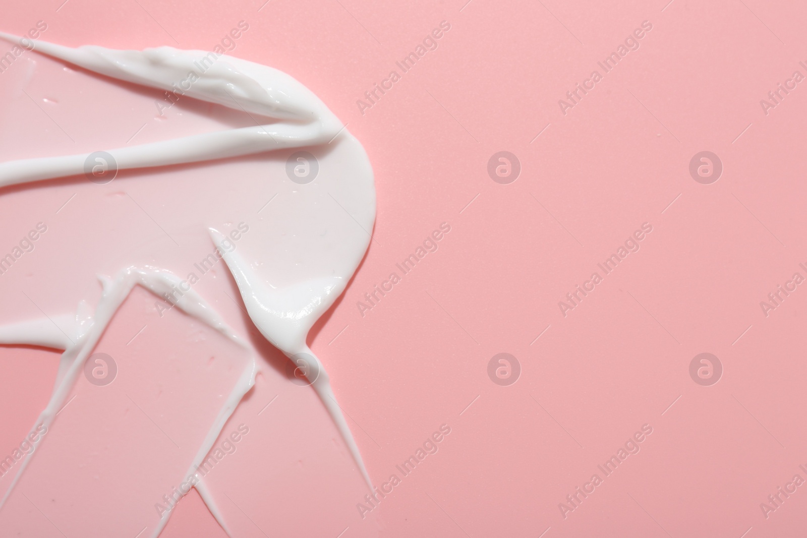 Photo of Sample of face cream on pink background, top view. Space for text