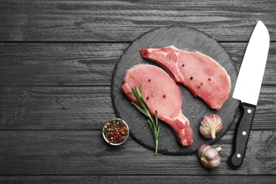 Flat lay composition with fresh raw cut meat on black wooden table. Space for text