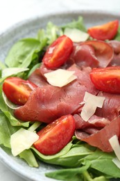 Photo of Delicious bresaola salad with tomatoes and parmesan cheese in bowl, closeup