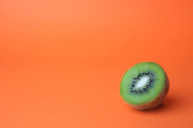 Photo of Cut fresh ripe kiwi on orange background, space for text