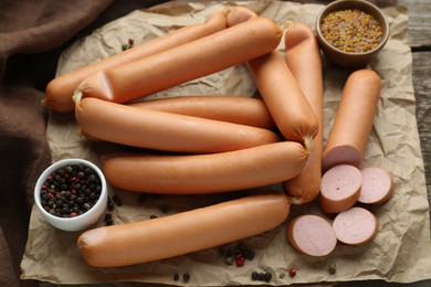 Tasty sausages, peppercorns and mustard on parchment paper, closeup. Meat product
