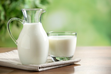 Photo of Fresh milk on wooden table against blurred background, space for text