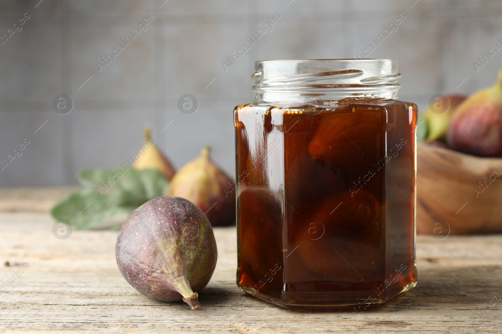 Photo of Jar of tasty sweet jam and fresh figs on wooden table