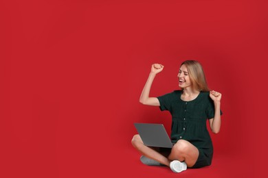 Emotional young woman with laptop on red background. Space for text