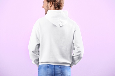 Man in hoodie sweater on color background. Space for design