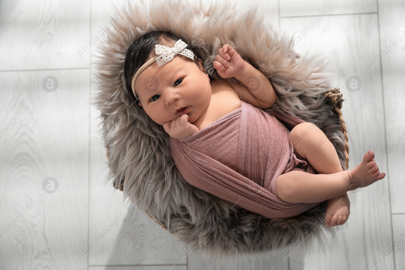 Photo of Cute newborn baby lying in wicker basket, top view