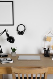 Photo of Home workplace. Laptop, lamp and stationery on wooden desk