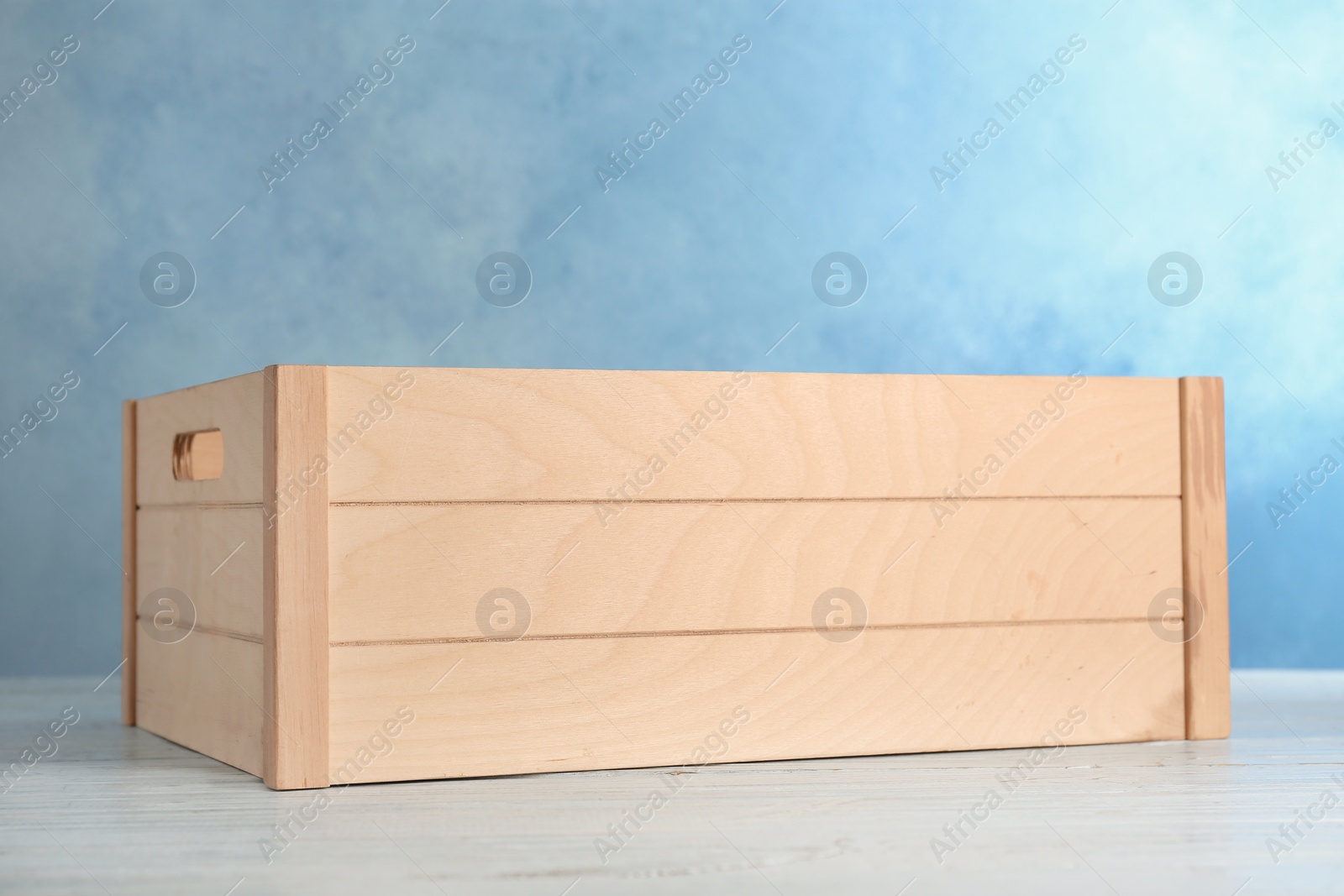 Photo of Wooden crate on table against color background