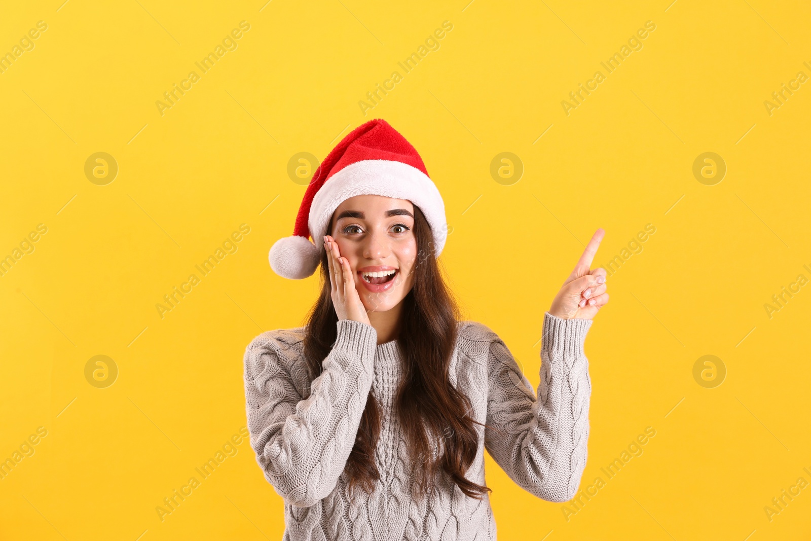 Photo of Beautiful woman wearing Santa Claus hat on yellow background