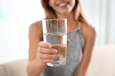 Photo of Woman holding glass with clean water at home, closeup