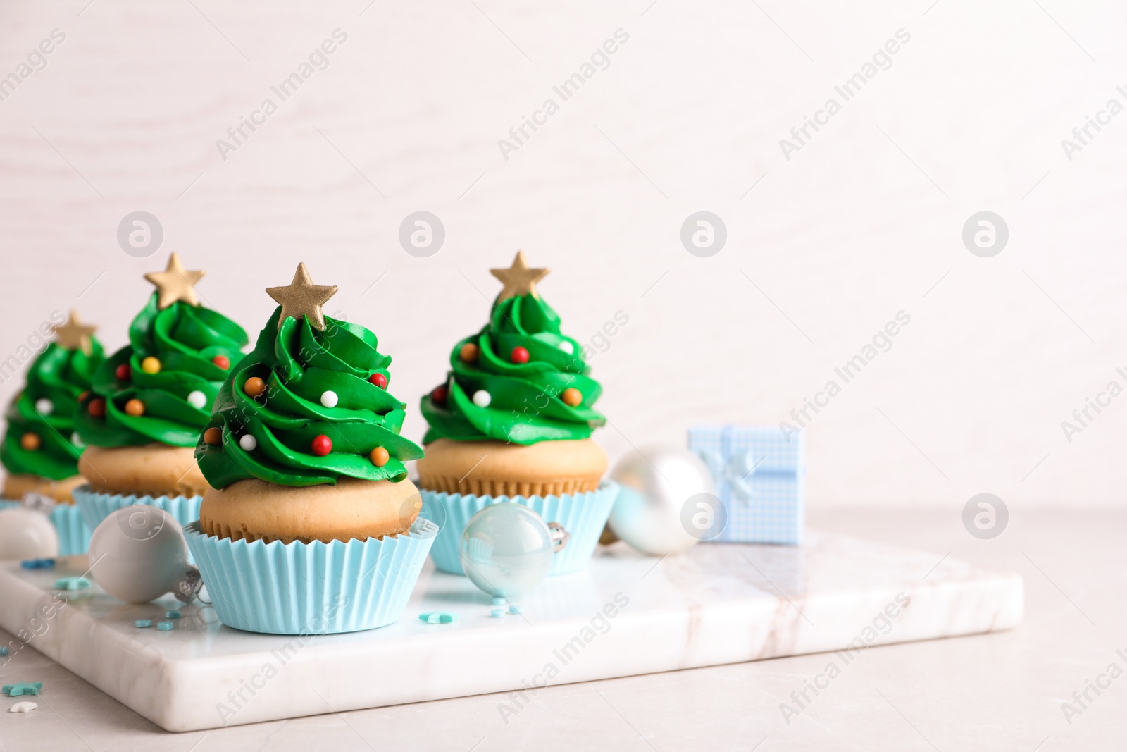 Photo of Christmas tree shaped cupcakes and decor on table. Space for text