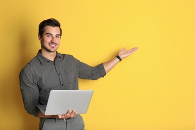 Photo of Young male teacher with laptop on yellow background. Space for text