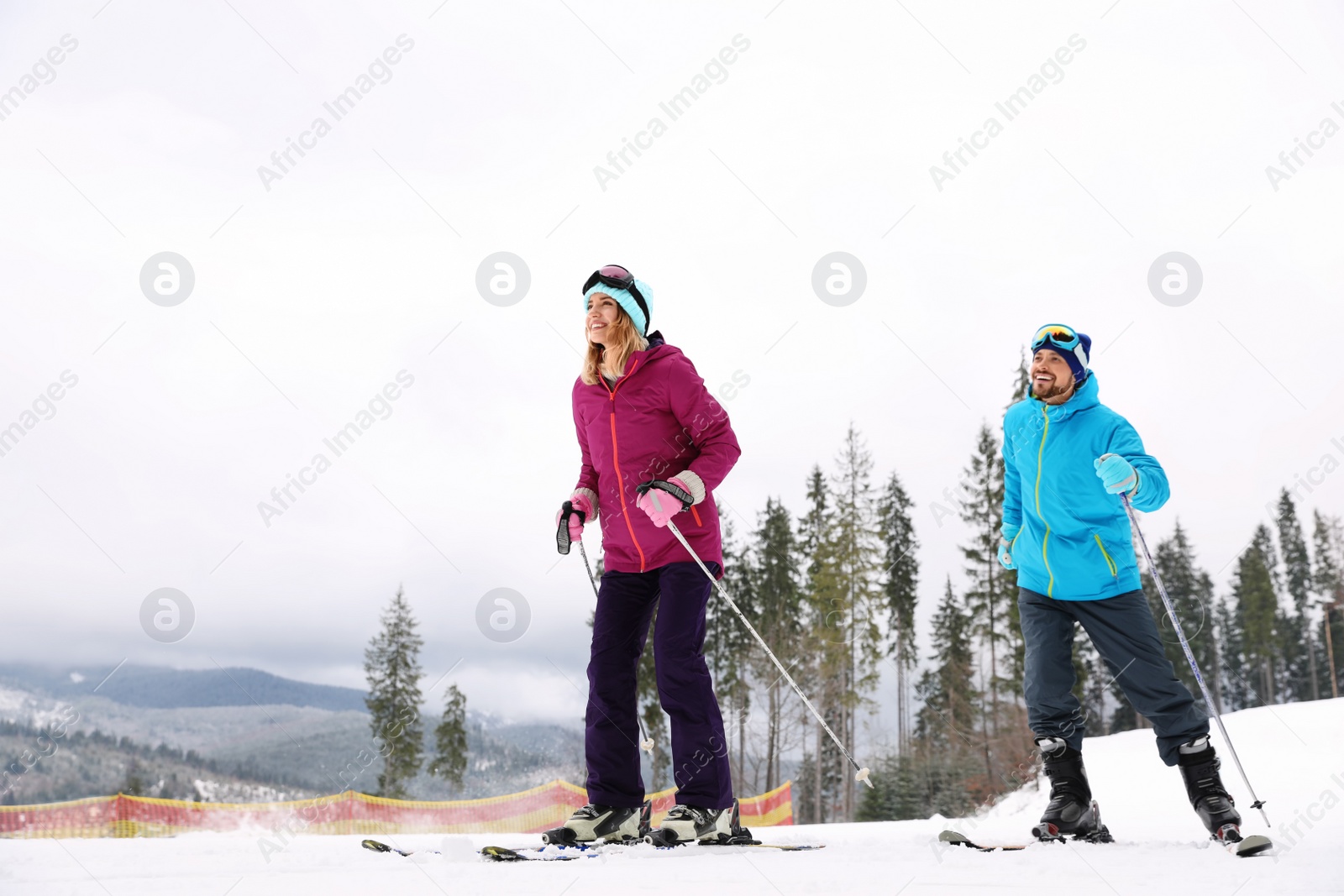 Photo of Couple of skiers on slope at resort. Winter vacation