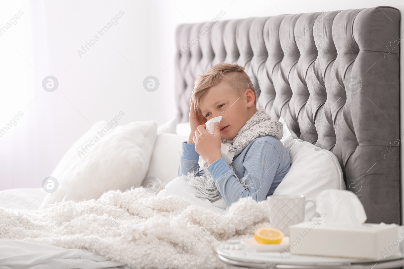 Photo of Sick little boy with tissue suffering from cold in bed