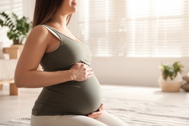Photo of Young pregnant woman practicing yoga at home, closeup. Space for text