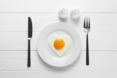 Photo of Romantic breakfast with heart shaped fried egg served on white wooden table, flat lay
