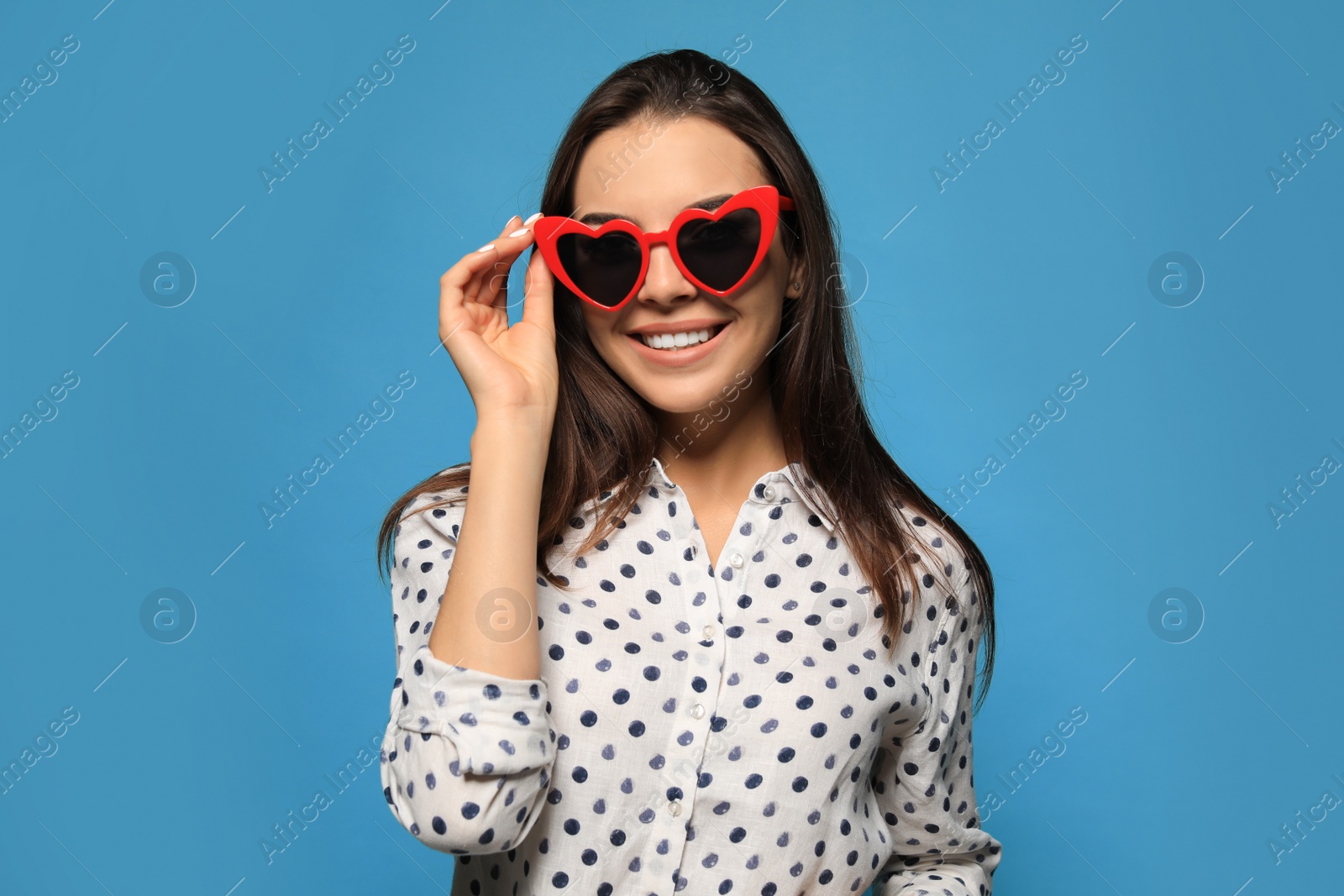 Photo of Portrait of beautiful young woman with heart shaped sunglasses on color background