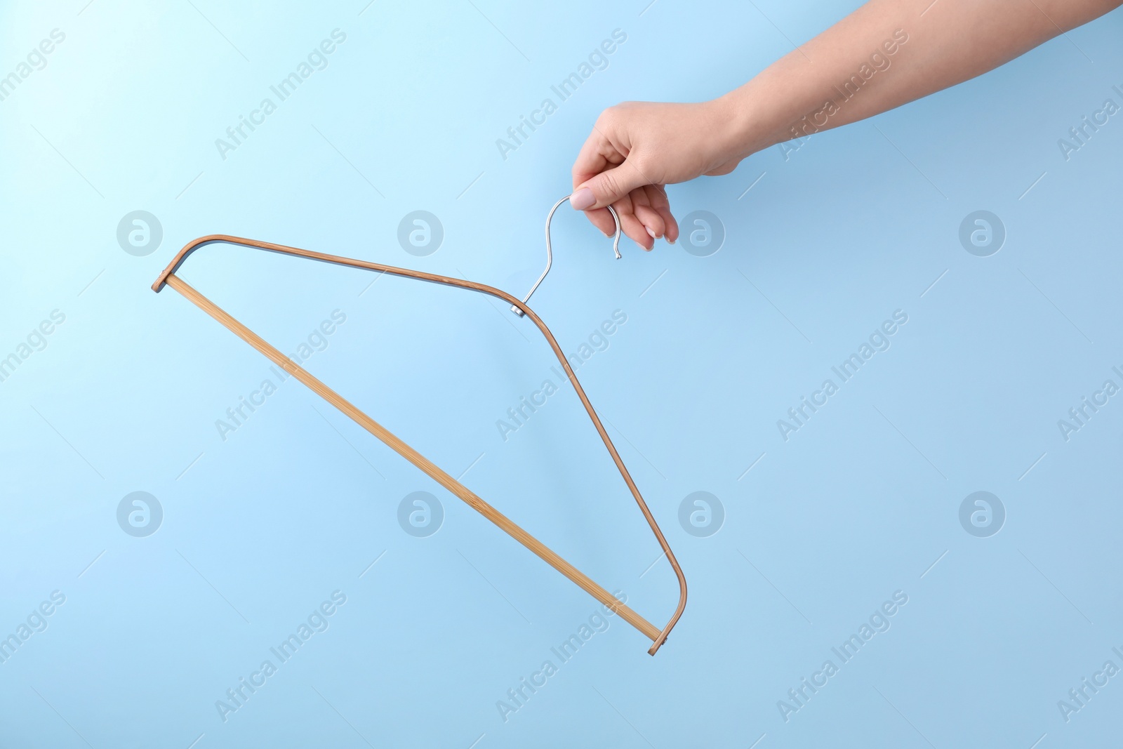 Photo of Woman holding hanger on light blue background, closeup. Space for text