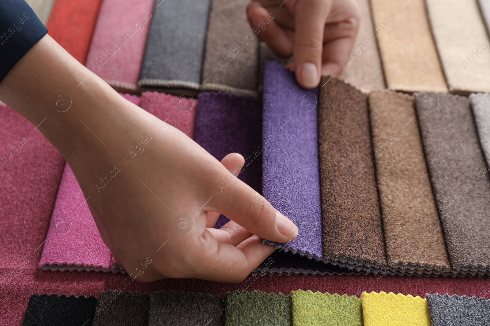 Photo of Young woman choosing among upholstery fabric samples, closeup. Interior design