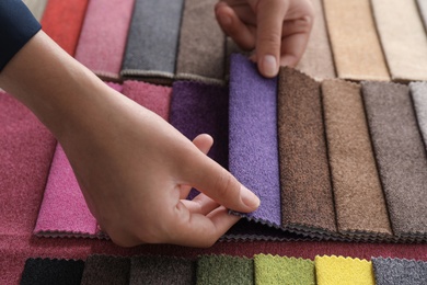 Young woman choosing among upholstery fabric samples, closeup. Interior design