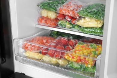 Plastic bags with different frozen vegetables in refrigerator