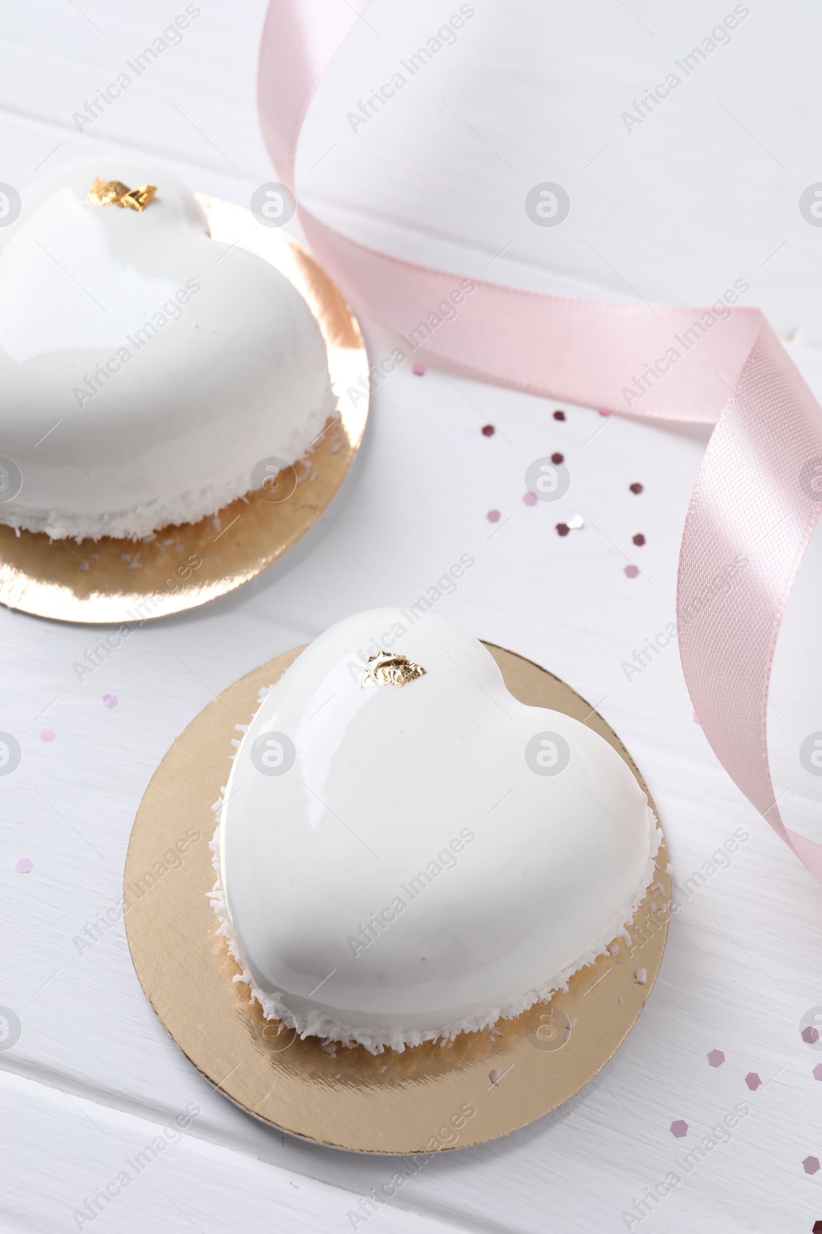 Photo of St. Valentine's Day. Delicious heart shaped cakes and confetti on white wooden table, closeup