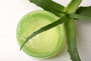 Jar of cosmetic gel and aloe vera leaves on white wooden table, top view