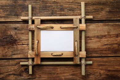 Photo of Empty bamboo frame on wooden table, top view