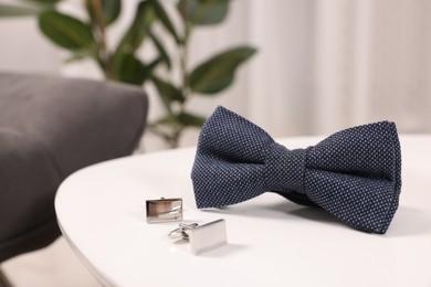 Photo of Stylish blue bow tie and cufflinks on white table, closeup