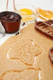 Cookie cutters and dough on white table, closeup