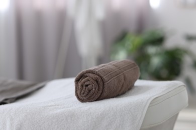 Photo of Rolled towel on massage table in spa center, closeup