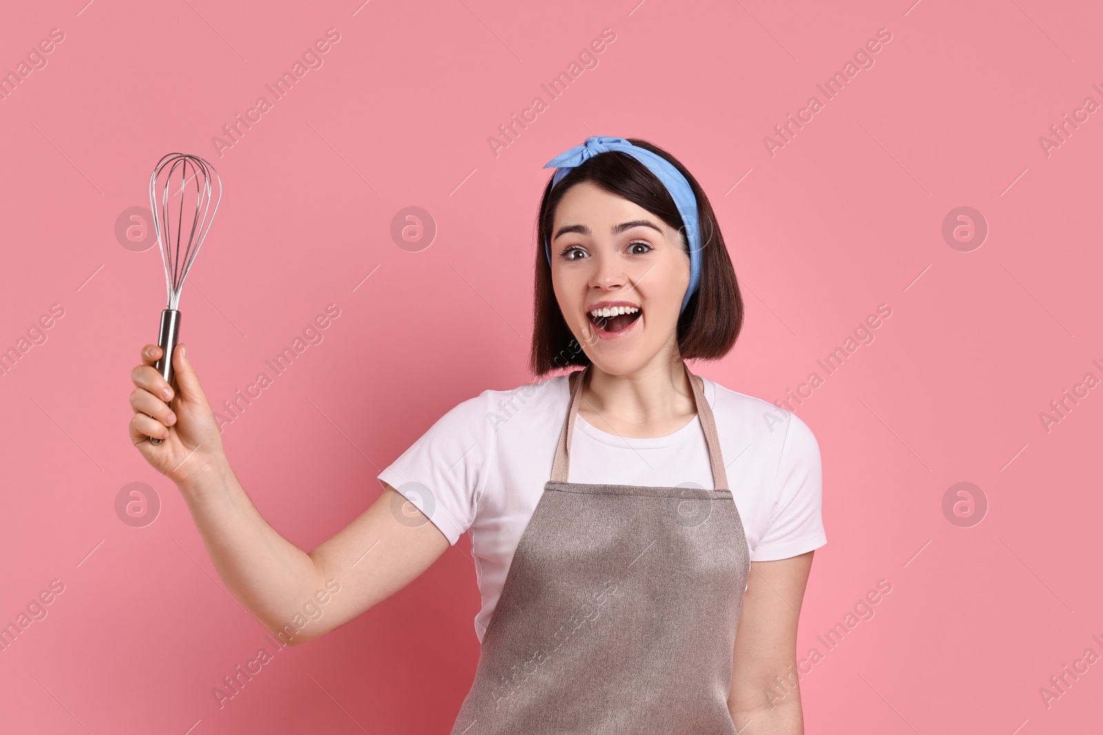 Photo of Happy confectioner with whisk on pink background