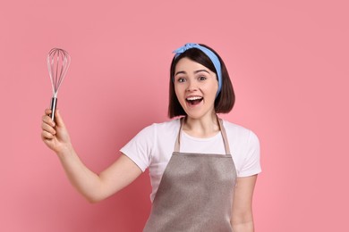 Happy confectioner with whisk on pink background