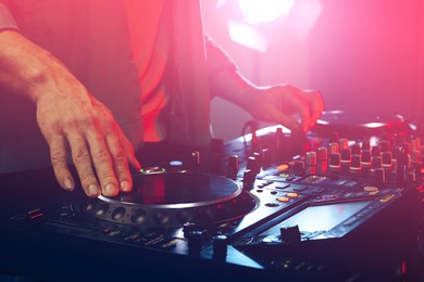 DJ creating music on modern console mixer in night club, closeup