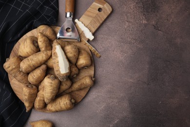 Photo of Tubers of turnip rooted chervil and peeler on brown table, top view. Space for text