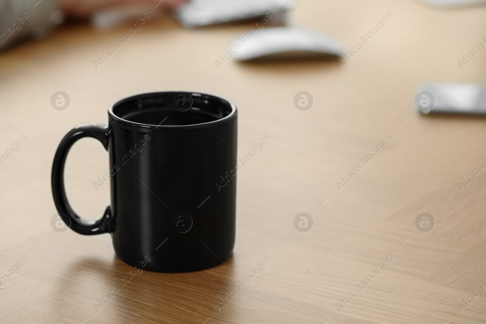 Photo of Black ceramic mug on wooden table at workplace. Space for text