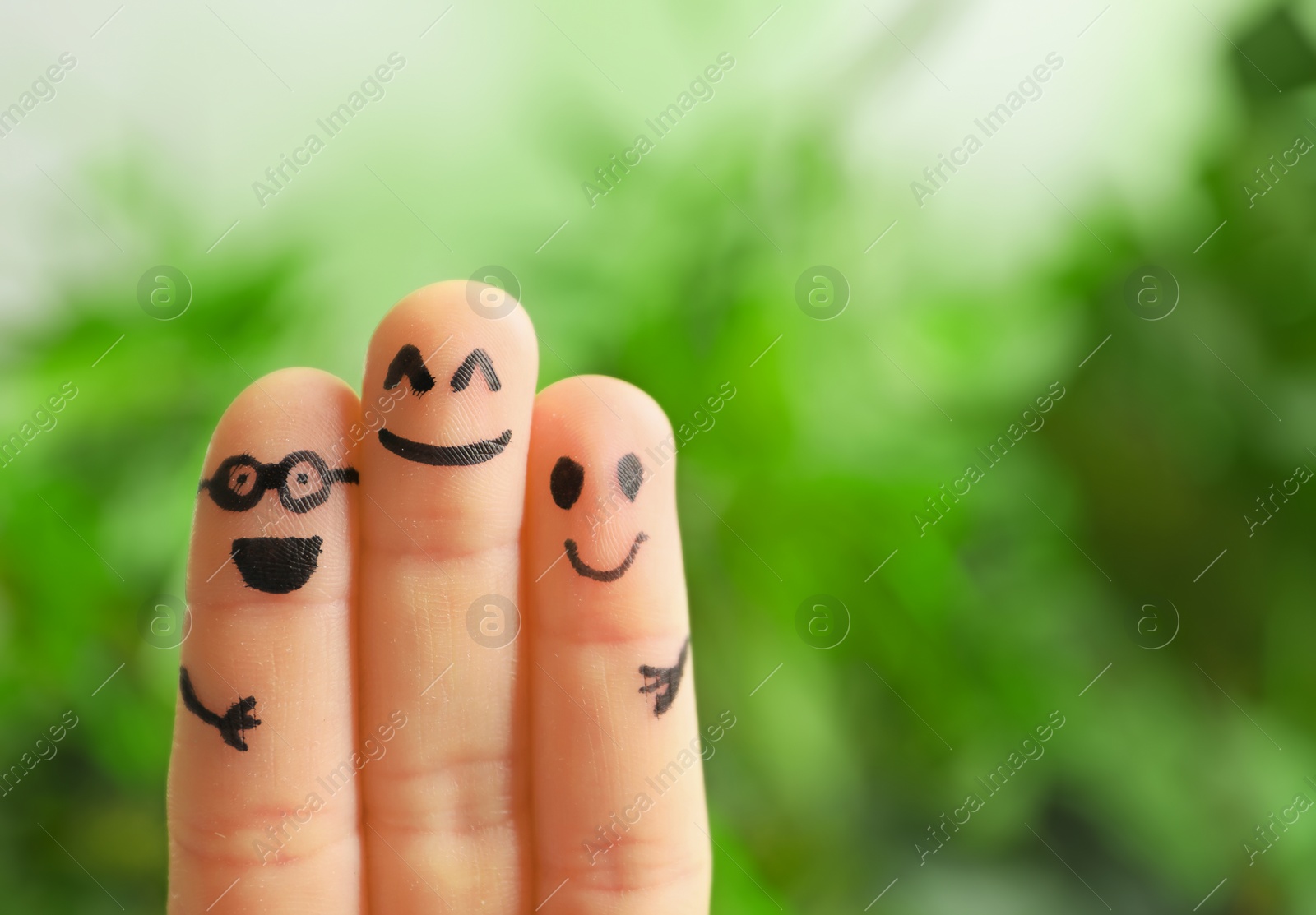 Photo of Fingers with drawings of happy faces against blurred background. Unity concept