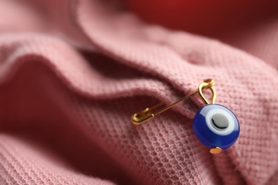 Evil eye safety pin on clothing, closeup