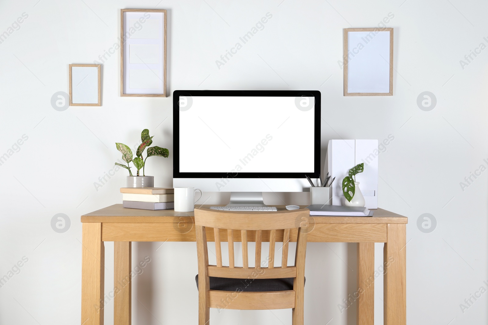 Photo of Home workplace. Computer, stationery and houseplants on wooden desk