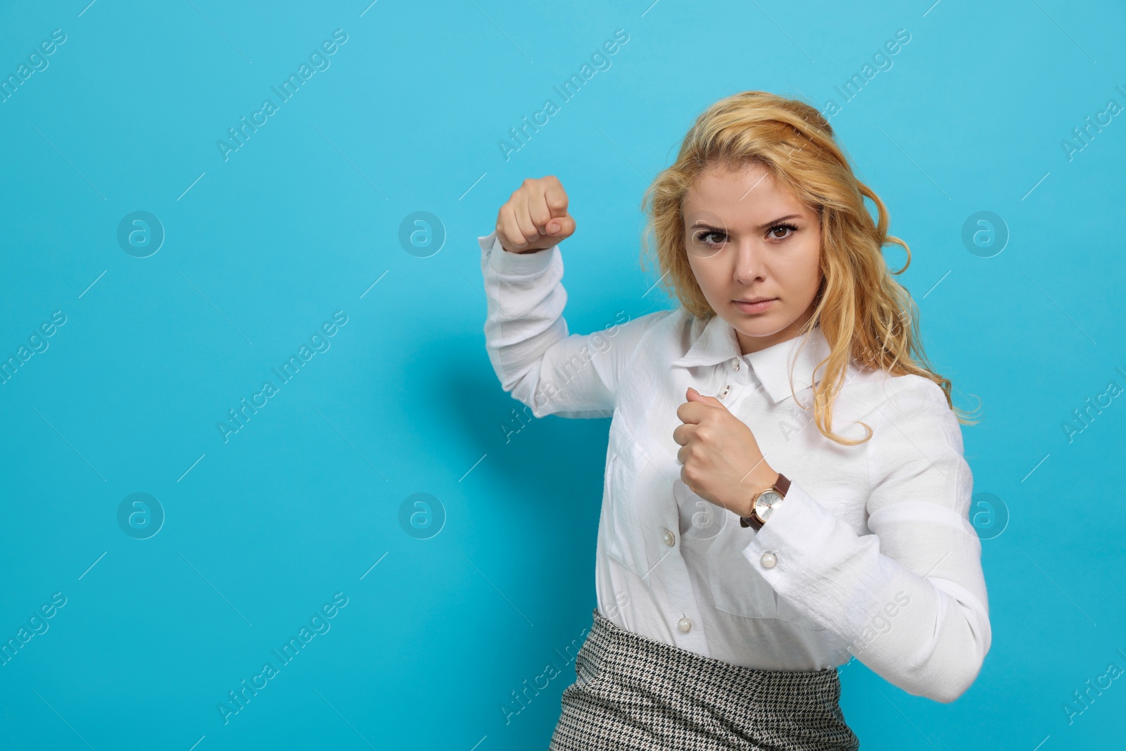 Photo of Young woman ready to fight on light blue background. Space for text