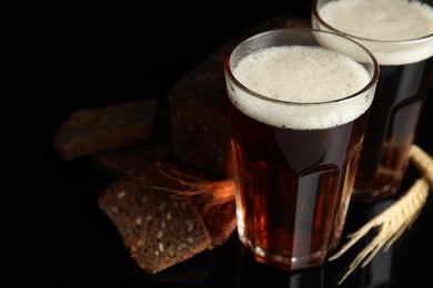 Photo of Delicious kvass, bread and spikes on black background