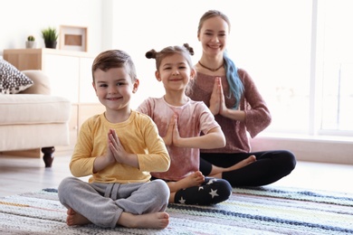Photo of Young mother and her children practicing yoga at home