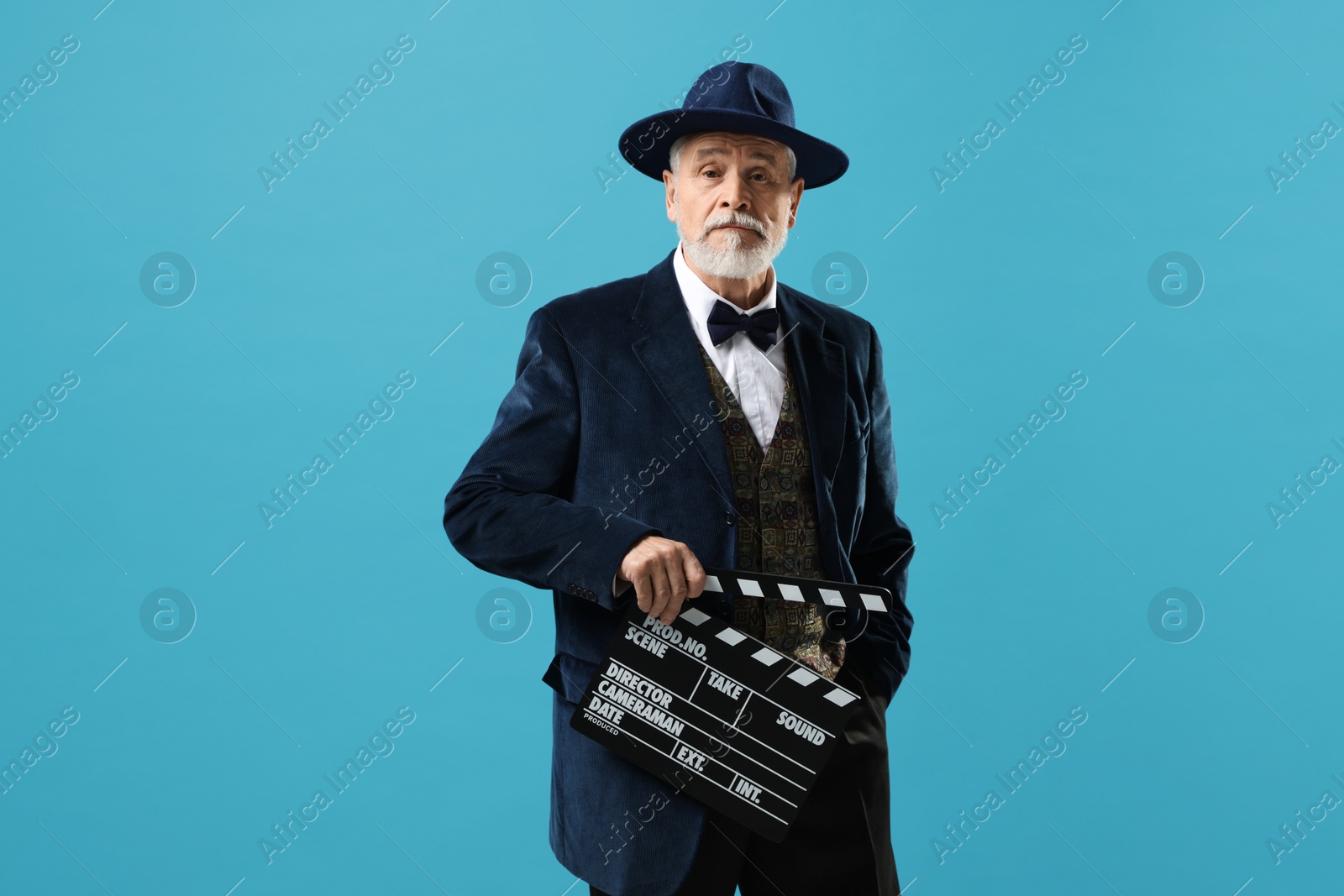 Photo of Senior actor with clapperboard on light blue background. Film industry