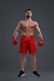 Photo of Man in boxing gloves on grey background, low angle view