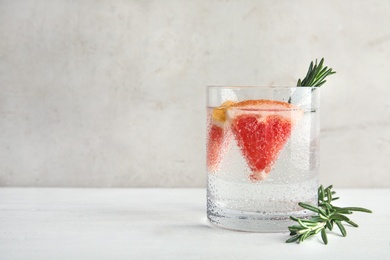 Photo of Glass of infused water with grapefruit slices on table. Space for text