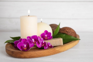 Photo of Tray with orchid flowers, candles and soap on white wooden table