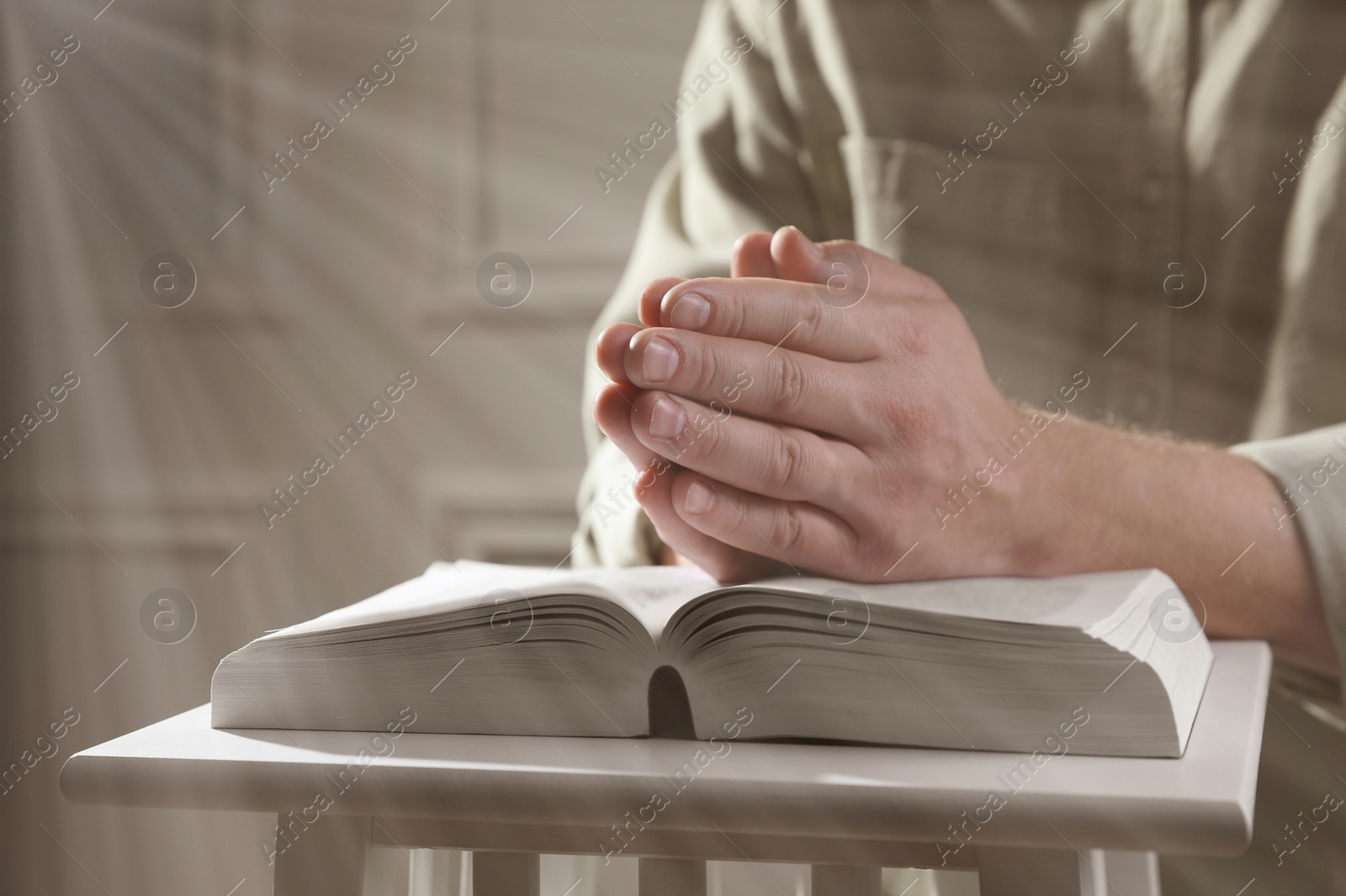 Image of Religion. Christian man praying over Bible at table, closeup