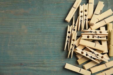 Photo of Pile of clothes pins on blue wooden table, flat lay. Space for text