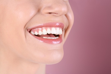 Young woman with healthy teeth and beautiful smile on color background, closeup. Space for text